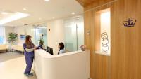 Receptionist and woman in scrubs talk at reception desk